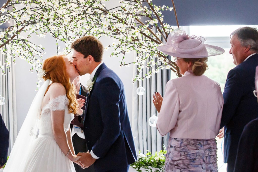 Bride and groom kissing surrounded by apple blossom