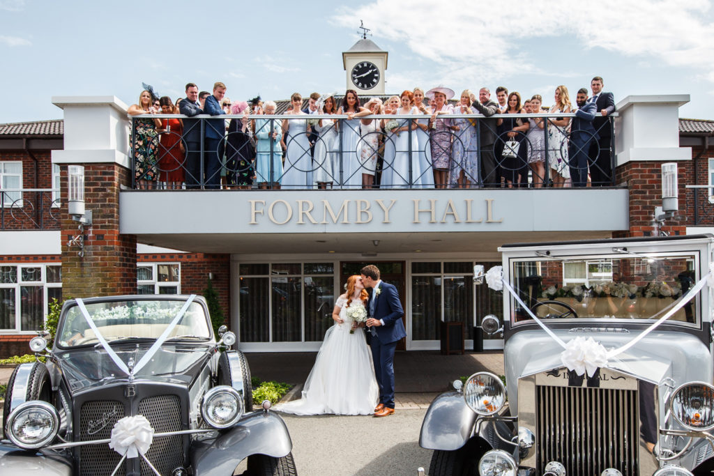 Bride and groom pictured at Formby Hall with guests on the balcony