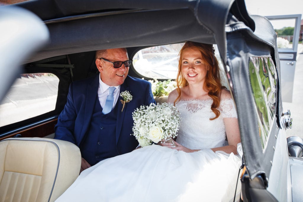 Bride with long red hair arriving with step dad in a vintage car