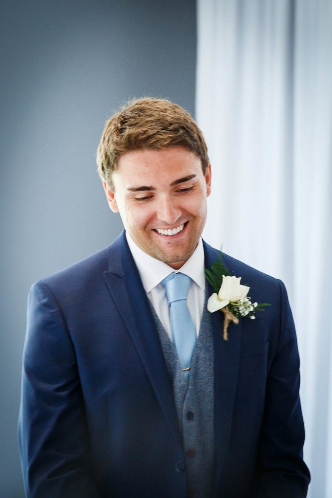 Groom in navy blue suit with white button hole