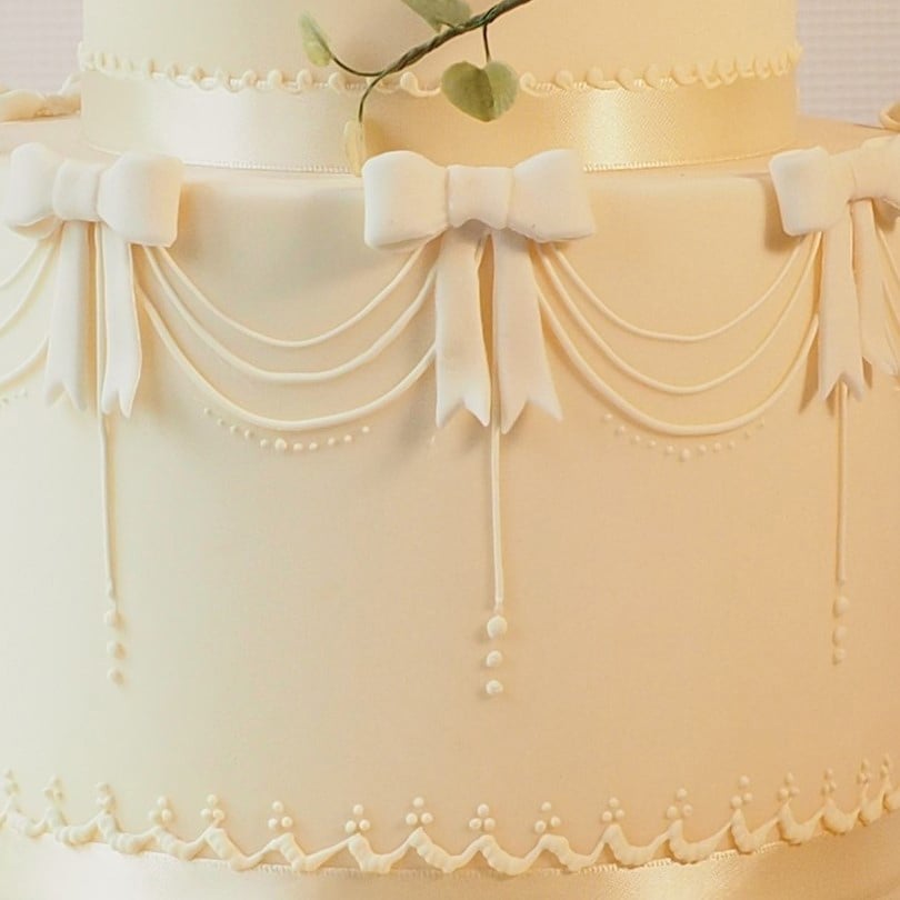 Royal icing detail on ivory cake, swags and bows