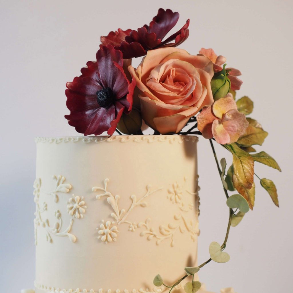 Top tier ivory wedding cake with hand piped royal icing and sugar flowers