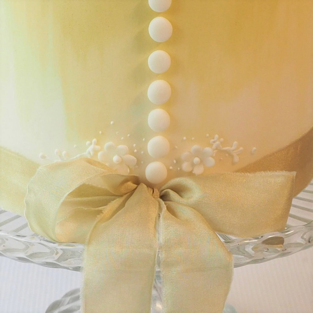 Close up of sugar button and bow detail on wedding cake