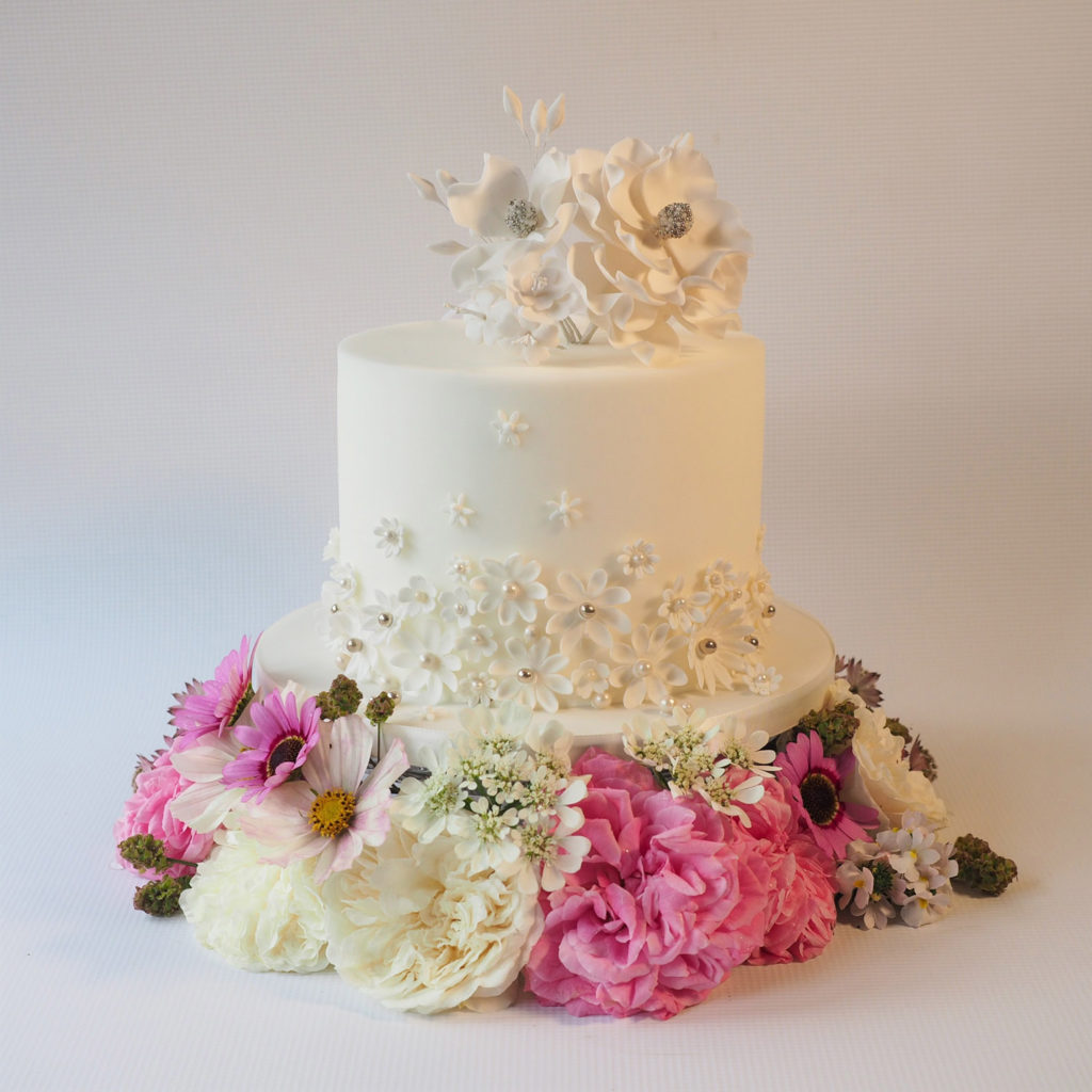 White contemporary wedding cake preseted on a flower crown