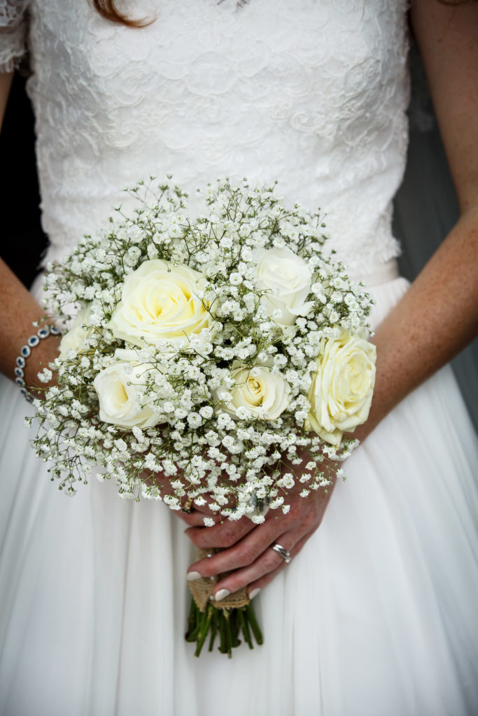 bride holding her bouquet ivory roses and masses of gypsophila