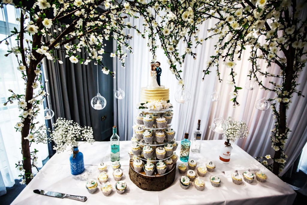 Cupcake tower surrounded by gin bottles top cake with couple bride and groom wedding cake topper