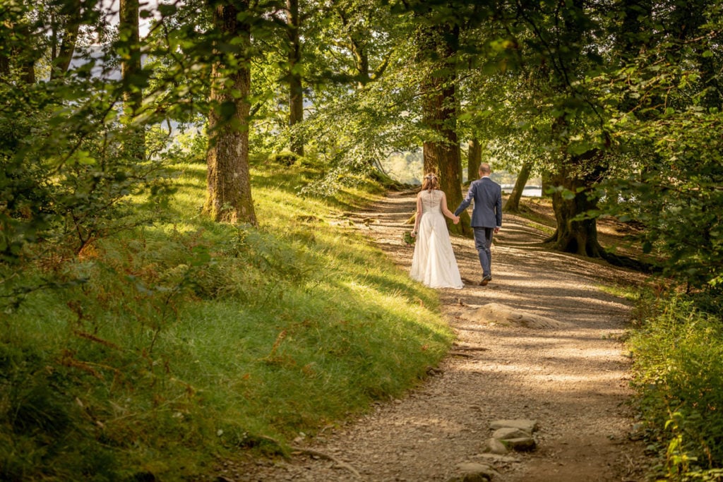 Bride and groom strolling in the woods at Cote How