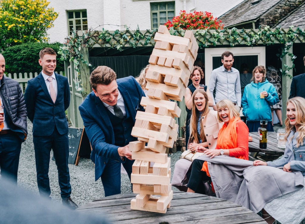 Groom and wedding guests having fun playing Jenga